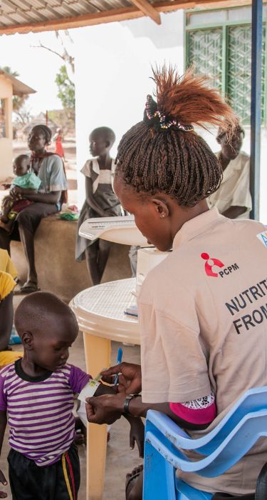 Sudan Południowy. Pracownicy Fundacji PCPM mierzy rączkę dziecku w centrum dożywiania w Gordhim.