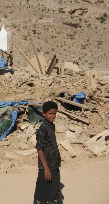 Jemen: chłopiec na tle zniszczeń.