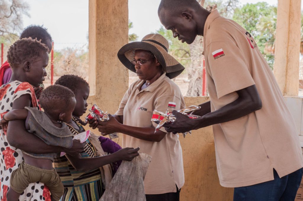 Sudan Południowy - pracownicy ośrodka wspieranego przez Fundację PCPM przekazują żywność terapeutyczną mamom dzieci.