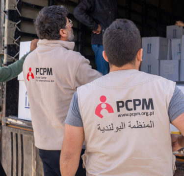 pracownicy humanitarni wyładowują paczki z pomocą humanitarną