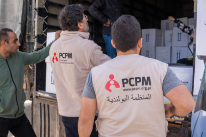 pracownicy humanitarni wyładowują paczki z pomocą humanitarną