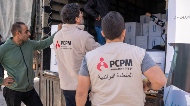 pracownicy humanitarni wyładowują paczki z pomocą humanitarną